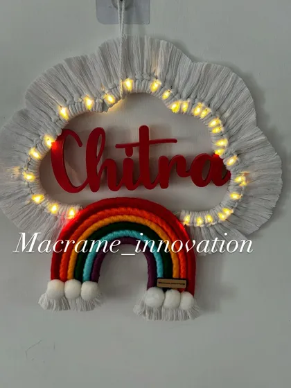 A custom name hanging for 'Chitra' glowing with warm fairy lights. The classic rainbow colors look so vibrant against the white cloud.