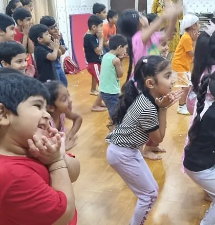 A close-up view of children learning a dance move with expressive faces. This image highlights the fun and focus the kids bring to our creative movement sessions.