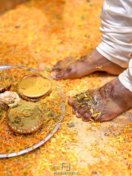 An artistic detail shot from the Haldi ceremony, focusing on the turmeric paste and flower petals. Capturing these small details adds texture and richness to the overall wedding story.