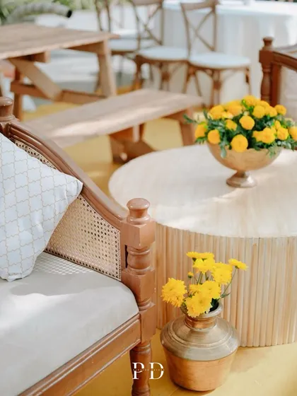 Another detail of the chic Haldi seating, showing the mix of textures with rattan-backed chairs, wooden benches, and brass and copper vases.