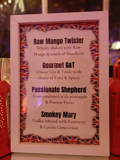 A custom-designed cocktail menu for the London-themed party. The menu features creatively named drinks like the 'Raw Mango Twister' and 'Passionate Shepherd', all framed with a Union Jack border.