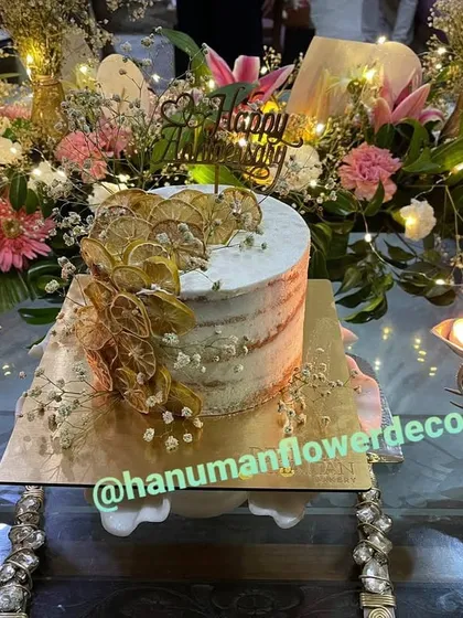 I can help you create a complete celebration centerpiece. This setup for a special birthday features a beautiful cake surrounded by a custom arrangement of fresh lilies, carnations, and baby's breath, accented with warm fairy lights.