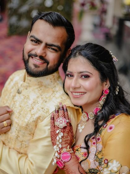 A happy close-up of a couple, with the bride showcasing her intricate hathphool jewelry.