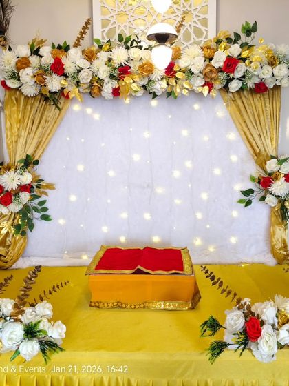 This is the same classic gold drape and floral setup, shown with a different lighting angle. The overhead light highlights the intricate floral arrangement on top, featuring red, white, and golden flowers.