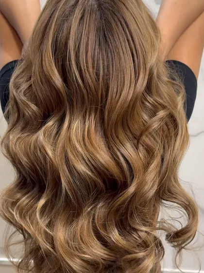 The final result of a beautiful blonde balayage, styled with soft, flowing waves.