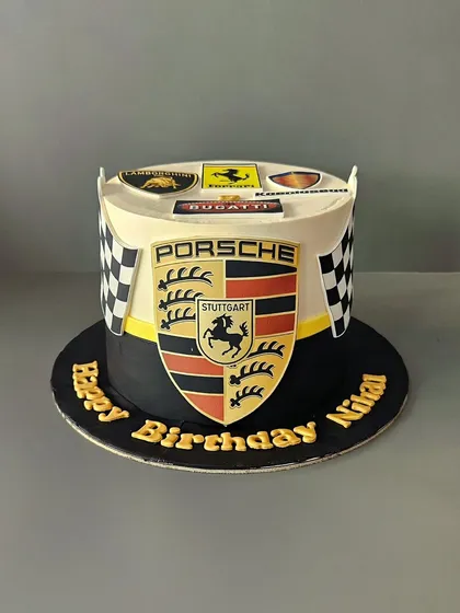 Rev up your celebration with this luxury car theme cake. Featuring the iconic Porsche logo and emblems of other supercars like Ferrari and Bugatti, this cake is perfect for the car enthusiast in your life. It's a sleek, classy design for a sophisticated birthday party.