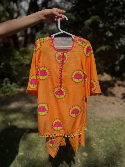 A closer look at my orange lotus-print kurta. The bright colors and playful pom-pom trim make it a fun and stylish choice for any casual outing or festive brunch.