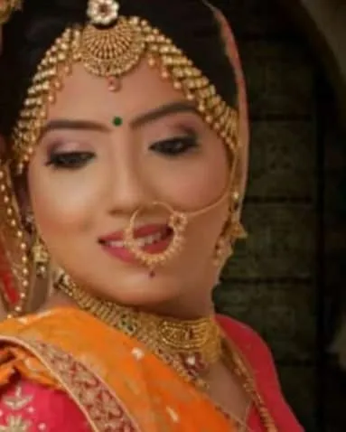 A close-up of a bride's face, showing the detailed eye makeup and the classic nose ring.