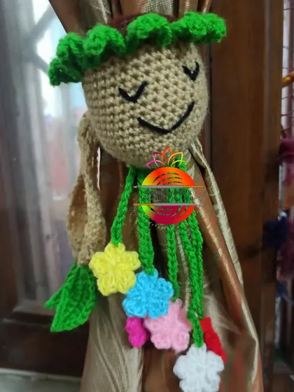 Inspired by a beloved movie character, this curtain tie-back looks like a happy little tree creature. It has a smiling face and a cascade of colorful flowers on its ties.