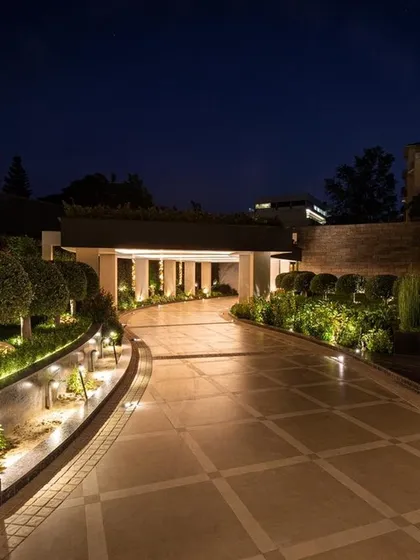 The entrance to a home sets the tone for everything within. Here, we designed a grand, illuminated driveway that is both welcoming and impressive, using a combination of ground lights, wall sconces, and accent lighting on the manicured shrubbery.