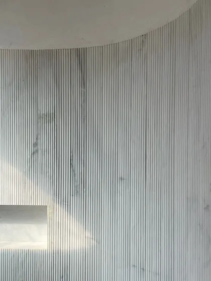 A play of materials at the House of Galleries. This fluted marble wall adds depth, texture, and character, with a built-in niche that catches the light.