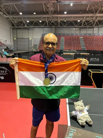 Gajanan Parmar proudly holds the Indian flag after his triumphant performance at the ITTF World Masters Championships, showcasing his gold medal.