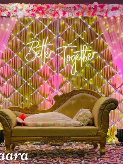 A popular choice for engagements and receptions, this stage combines a glamorous quilted gold backdrop with soft pink draping and a custom neon sign. It’s a modern, chic, and highly photogenic setup for any celebration of love.