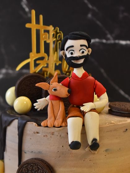 A close-up of the adorable, personalized man-and-dog figurine, showing the detail and care that goes into these custom toppers.