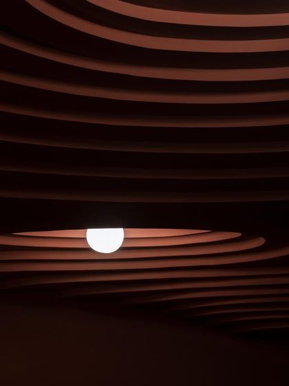 A detail from our award-winning 'Whispers in Motion' project. The dramatic, layered ceiling is sculpted to create a sense of rhythm and depth, with a single light source emerging like a pearl from within the form.