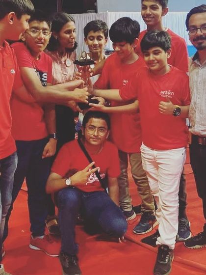 The team huddles around their "Best Team in Research Innovation" trophy. This award recognizes their ability to identify a real-world problem, research it thoroughly, and propose an inventive solution.