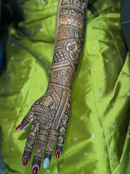 A full bridal arm demo against a vibrant background. This design is rich with traditional patterns, including paisleys and detailed grid work, showing the level of artistry we aim for.