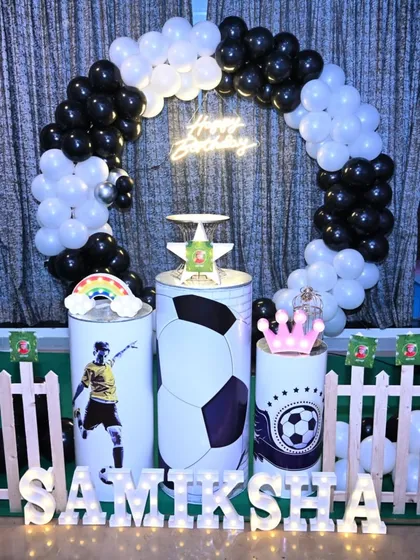 A clear view of the football-themed birthday stage. The black and white balloon arch, custom pedestals, and marquee letters create a cohesive and sporty look.