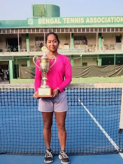 Shruti Gupta stands proudly on the court with her Women's Singles championship trophy at the Bengal Tennis Association.