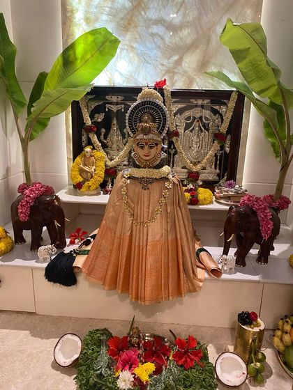 A simple yet elegant pooja setup, where the Goddess is adorned in a beautiful peach-colored silk saree.
