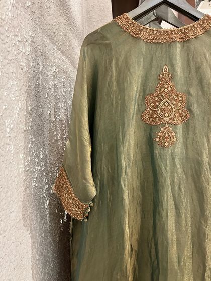 A close-up of an olive green silk kurta, featuring a beautifully detailed gold embroidered motif on the side.