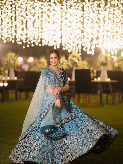A smiling portrait in the blue floral lehenga, showcasing a look that is both elegant and joyful for a wedding celebration.