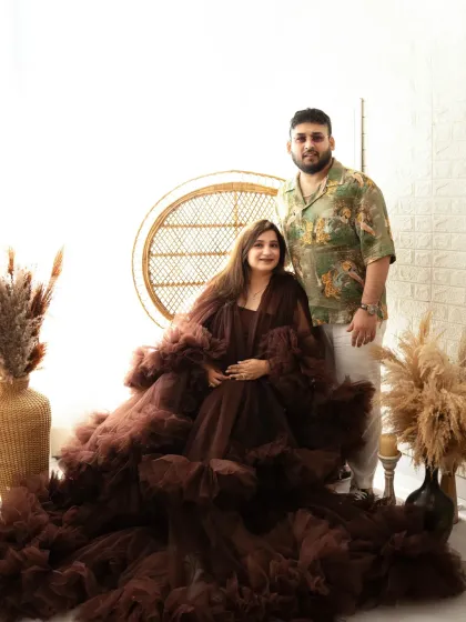 A lovely portrait of an expecting couple. They are posed together in our studio, with the mother-to-be seated in an elegant ruffled gown.