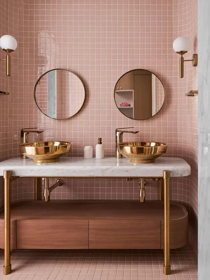 In this kid's bathroom, I designed a custom vanity with a marble top and brass legs to hold two statement golden sinks. The playful pink tile is balanced by the sophisticated materials, creating a space that is both fun and elegant.