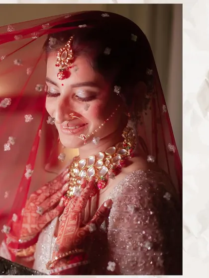 A close-up shot of the bride under her red veil. Her gentle smile and closed eyes convey a sense of peace and happiness, capturing the intimate emotions of the wedding day.