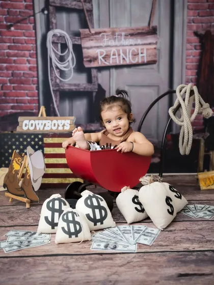 The full ranch setup for this little buckaroo, complete with a rustic backdrop and cowboy props.