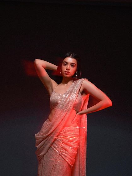A studio shot using colored gels to create a moody, artistic effect. The red light adds drama and intensity to this portrait, showcasing a modern sequined saree in a new light.