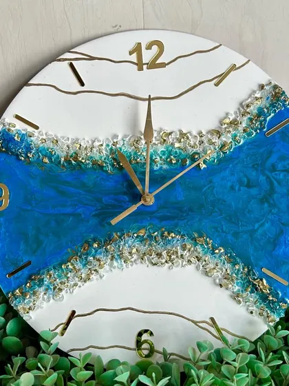 This geode-inspired clock features a river of deep blue resin flowing through a clean white base, accented with gold crystals and lines.