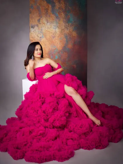 For the mom who loves to make a statement, this vibrant pink ruffled gown is pure joy. It shows how your maternity shoot can be a high-fashion experience, celebrating motherhood with confidence and style.