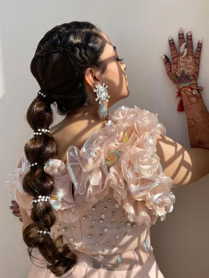 A profile view of the balloon ponytail, showcasing the bride's henna and the hairstyle's intricate details.