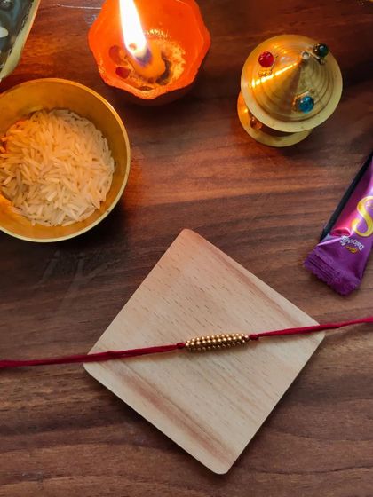 My most affordable rakhi design, priced at 20 rupees. This simple yet beautiful rakhi is made with golden beads on a red thread.