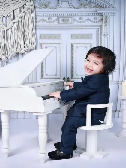 A joyful moment of music-making. The all-white, elegant set provides a beautiful contrast to the sharp navy suit, creating a striking and happy portrait.