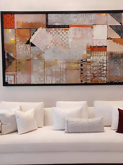 A pristine white sofa provides a tranquil canvas for a collection of hand-embroidered and textured cushions in varying shades of white and a single deep burgundy accent. This composition highlights our mastery of minimalist elegance and the art of subtle, layered texture.