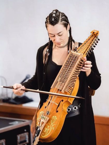 A close-up of the artist playing the Nyckelharpa, a traditional keyed fiddle. Its unique sound adds a magical quality to the lullabies featured in 'Pajarillo Verde'.