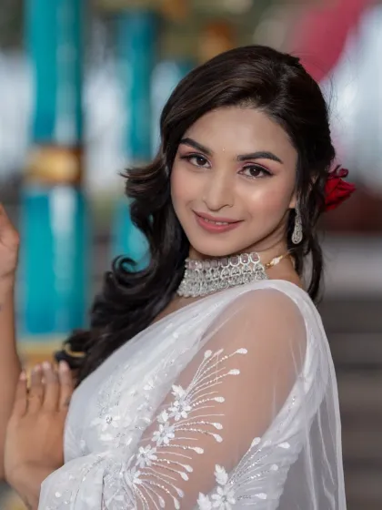 A soft and angelic look for a party or pre-wedding shoot. The white saree is complemented by soft pink makeup and a simple, elegant hairstyle.