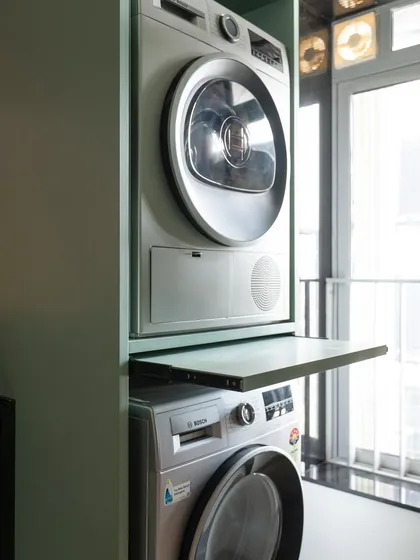 This stacked washer and dryer unit includes a clever pull-out shelf in between, providing a convenient surface for folding clothes right as they come out of the dryer. It’s a small detail that makes a big difference in functionality.