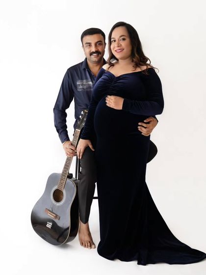 A creative couple's portrait where the partner holds a guitar, adding a personal and musical touch to their maternity session.