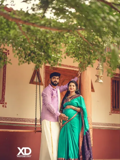 A classic couple's pose at a traditional South Indian style home. The setting, with its wooden pillars and swing, provides an authentic and rustic charm.