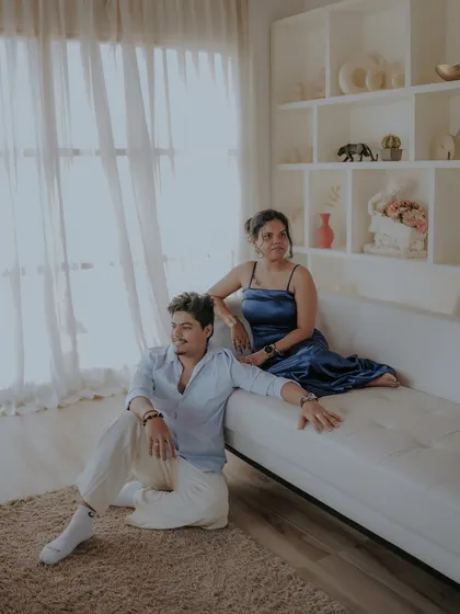 A relaxed and stylish portrait from an indoor pre-wedding shoot. The clean, white aesthetic of the studio set creates a modern and chic vibe.
