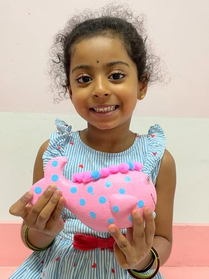 A side view of the cute pink whale planter, showing the polka dots and pom-pom details.