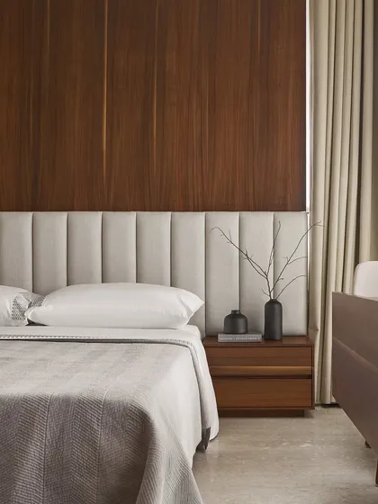 The master bedroom's custom headboard and walnut wood paneling create a warm, inviting backdrop. The multifunctional table sits elegantly by the window, proving that practical, transforming furniture can also be a beautiful design element.