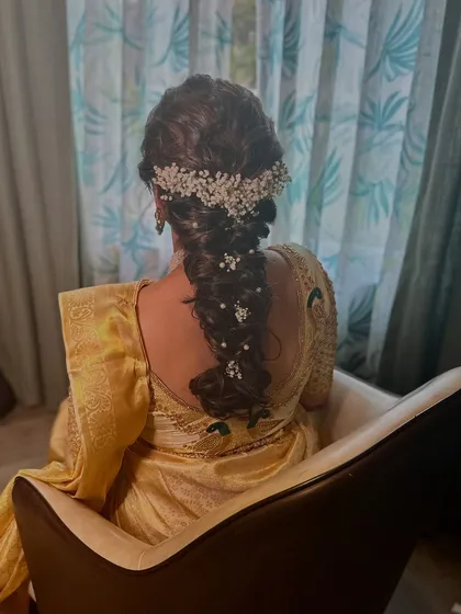 A view of the intricate bridal braid, beautifully woven with baby's breath. This hairstyle adds a touch of modern romance to the traditional South Indian look.