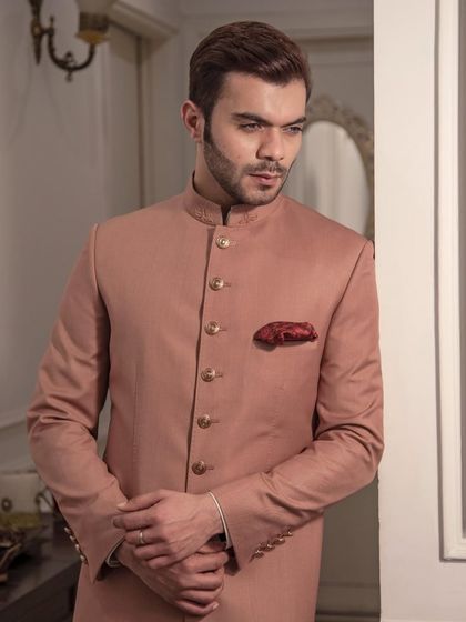 A classic sherwani in a dusty rose color. Crafted from luxurious fabric with intricate detailing, this piece offers a timeless sophistication for any grand occasion.