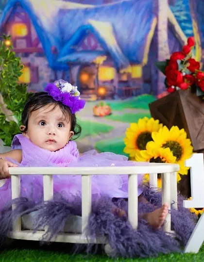 Celebrating six months with a magical, fairy-tale theme. The purple dress and whimsical cottage backdrop create an enchanting scene.