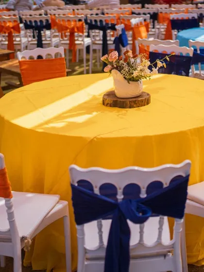 For a Mexican themed Mehendi, we used a vibrant color palette of yellow, orange, and royal blue. The table settings are simple yet impactful, using colorful linens and fabric chair ties instead of disposable decorations.