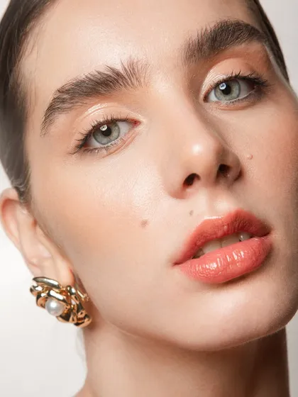 A detailed close-up of the lips and skin. I created a peachy, glossy lip and luminous skin, a popular combination for spring and summer beauty campaigns.